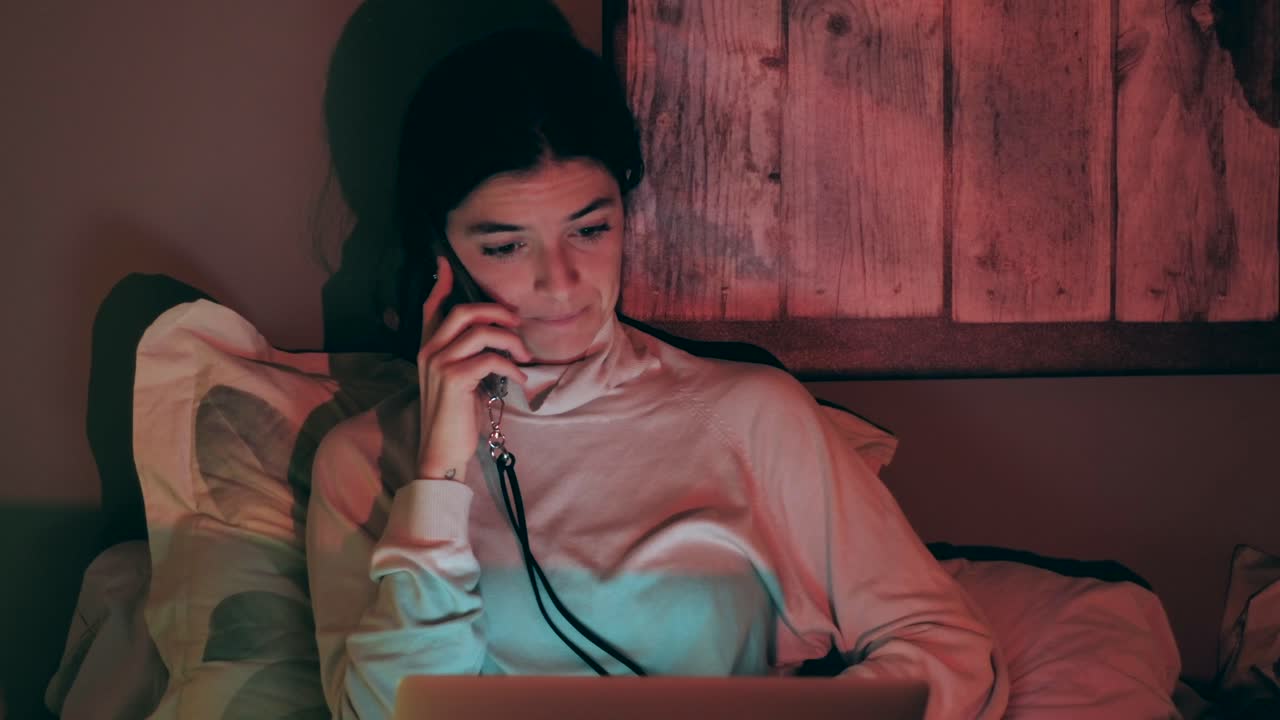 mujer disfrutando de una agradable conversación por teléfono con una computadora portátil por la noche en casa