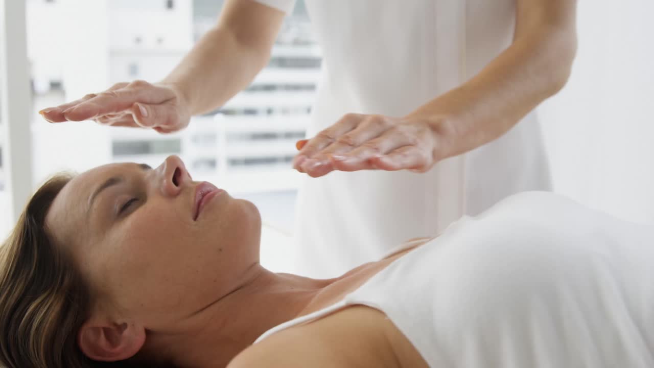 치료사가 환자 위에 손을  ⁇ 고 있습니다.