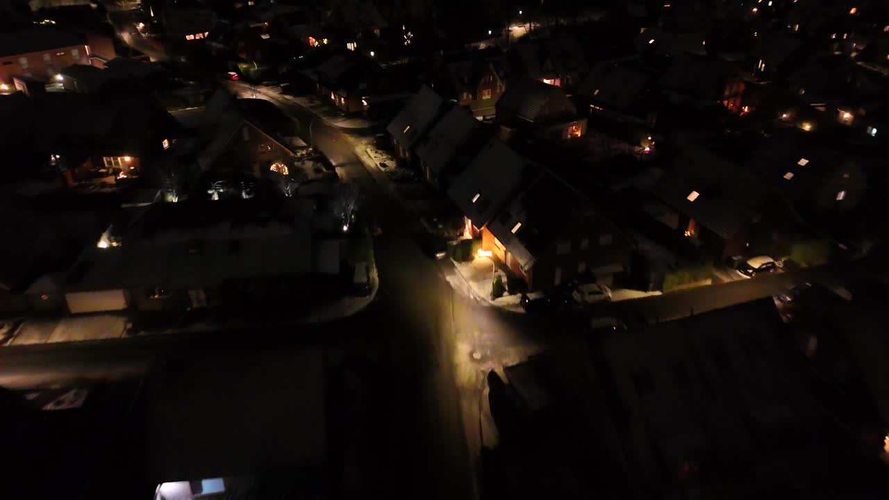 Warm lighting lantern in American neighborhood at night. Snowy winter day in housing area. Illuminated small town in USA in cold January. Aerial approaching shot.