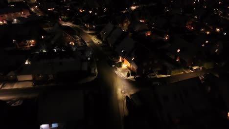 warm lighting lantern in american neighborhood at night. snowy winter day in housing area. illuminated small town in usa in cold january. aerial approaching shot.
