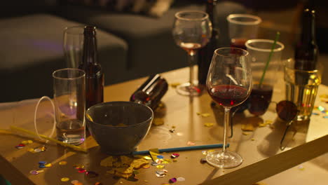 close up of messy table covered with empty wine glasses and beer bottles after house party 1