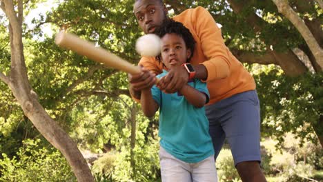 father is helping his son to play baseball