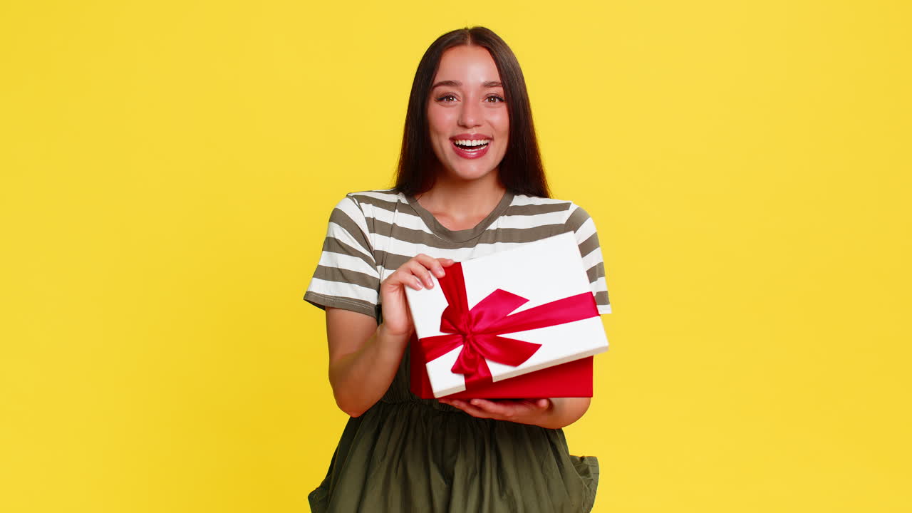 Woman opening birthday gift box with surprised happy expression joyful emotional reaction to present