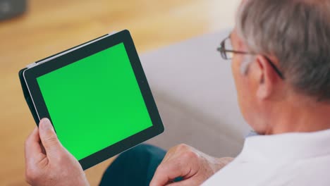 un abuelo usa una tableta con una pantalla verde
