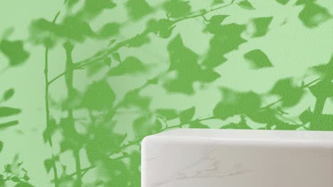 white marble pedestal with shadow of branches on a green background