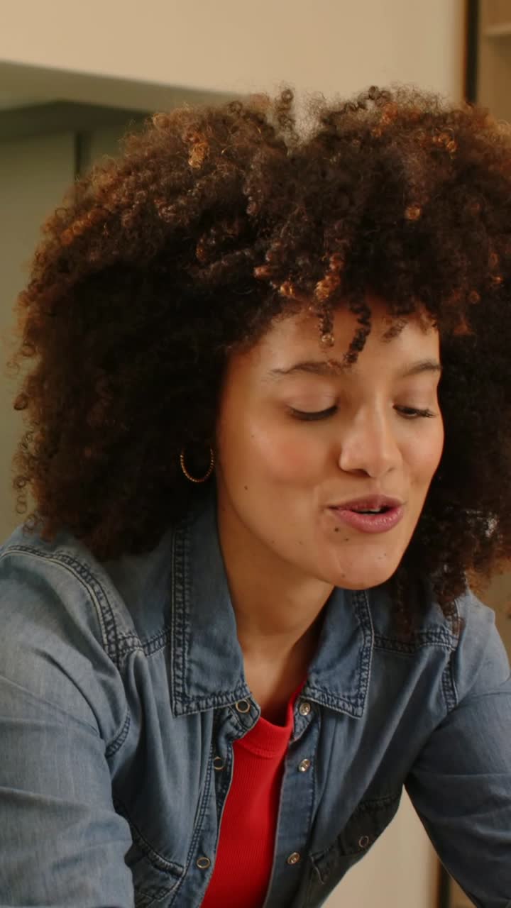 Vertical video: After friend's gesture, woman in denim jacket preparing food in kitchen with board