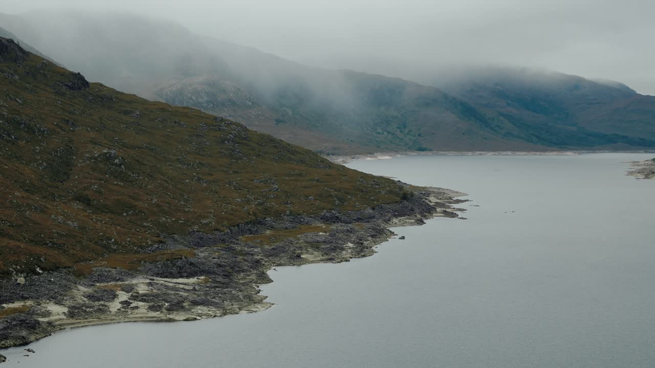 Circling left aerial of Loch Cluanie with Highlands rain on distant peaks, Scotland