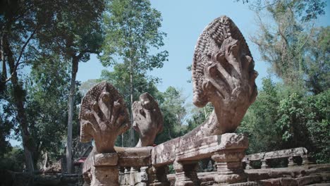 Ancient-stone-naga-balustrades-in-Angkor-Wat-under-blue-sky,-Cambodia