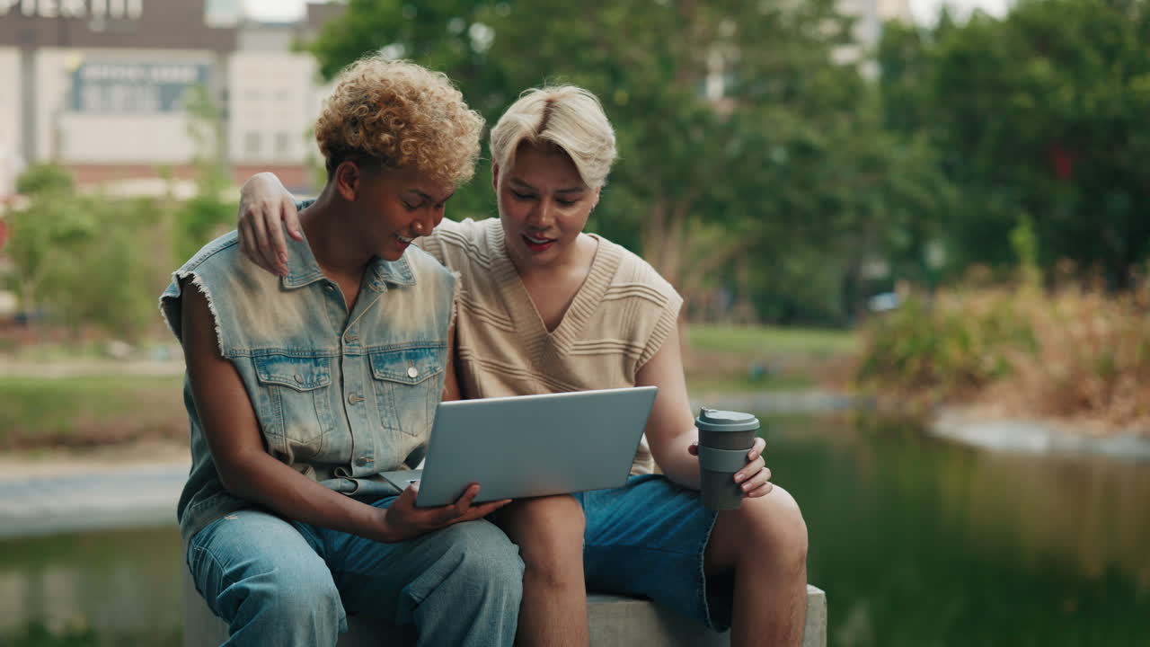 Two Young Adults Using Laptop in Park