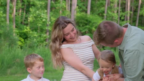 a heartwarming video featuring a family of four posing for a picture in a lush green park a heartwarming video of a family of four posing for a picture in a green park the pregnant woman is kissed by her husband while their two children stand by creating a beautiful family moment