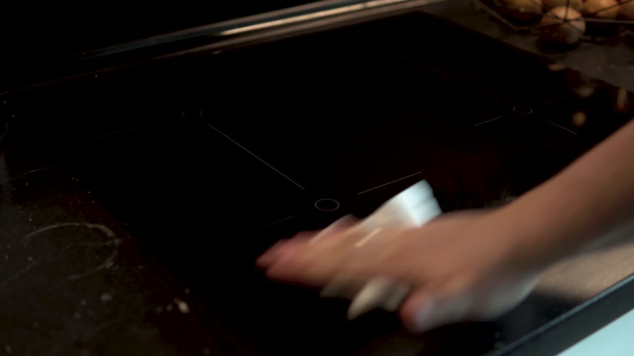 흰색 키친타월로 인덕션 레인지를 청소하고 있어요