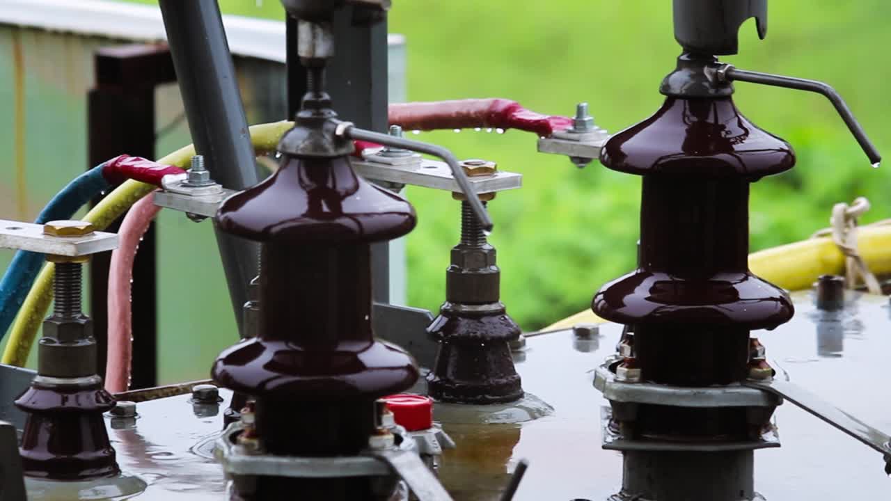 Electric power transformer during rain Close-up footage. Wet insulators and cables show real-time outdoor power infrastructure under harsh weather conditions. Ideal for industrial visuals