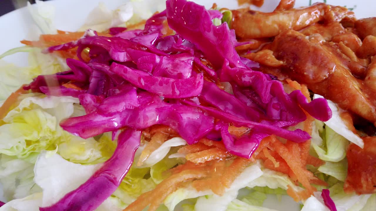 테이블 위의 샐러드 위에 올리브 오일을 붓는 손의 모습