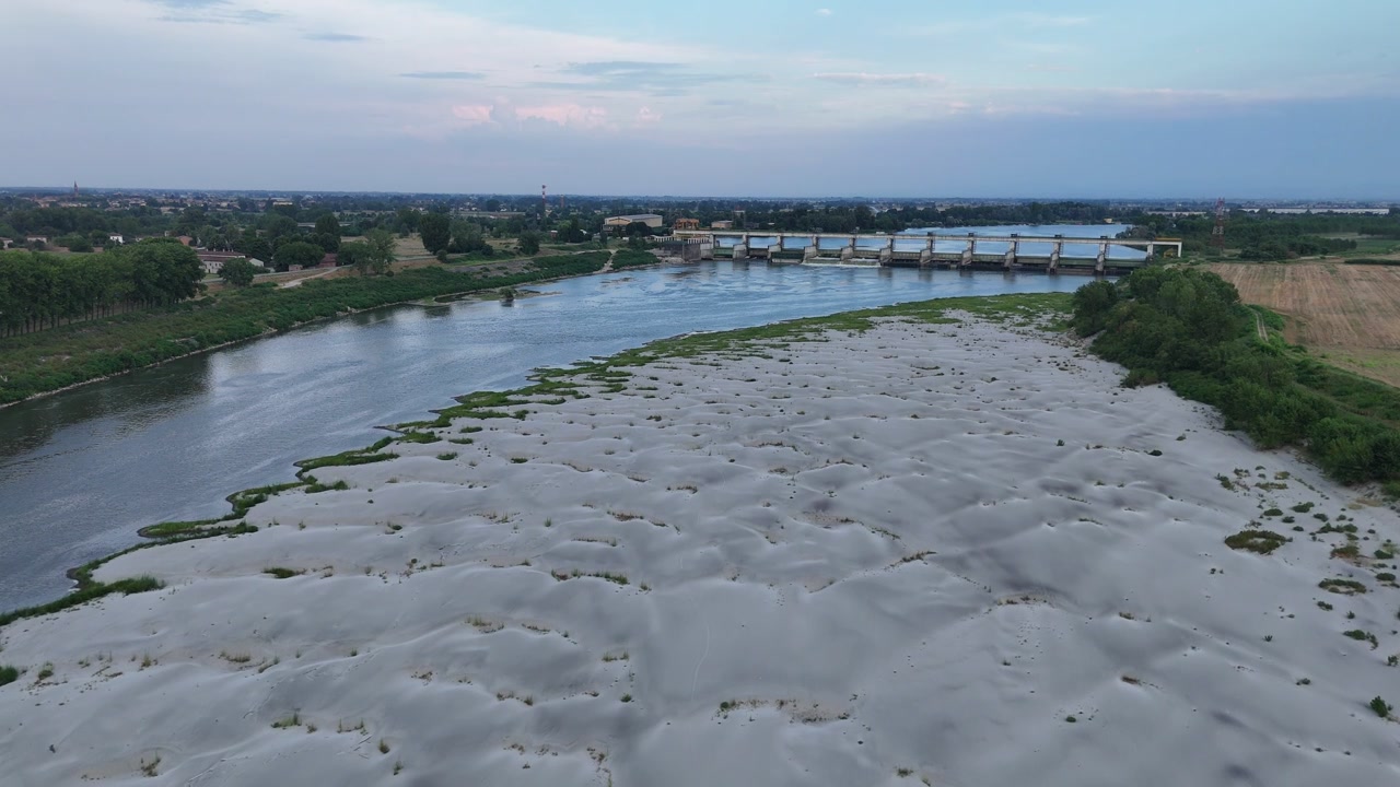 Isola Serafini Barajı'ndaki Po Nehri, Monticelli d'Ongina, Piacenza, Emilia-Romagna, İtalya, 2026 sıcak hava dalgası sırasında geniş açık çakıl setlerini, örgülü düşük akışlı kanalları ve azalmış debiyi ortaya koyuyor.