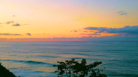 HD-Hawaii-Kauai-slow-motion-static-wide-shot-over-tree-and-ocean-with-waves-in-lower-left-crashing-in-from-right-to-left-with-a-beautiful-sky-near-sunset