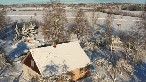 aerial view of snowy countryside cottage roof and smoke come out from chimney