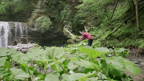 Fotograf-Mit-Rotem-Pullover-Läuft-Herum-Und-Versucht,-Eine-Komposition-Für-Den-Wasserfall-Zu-Finden