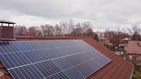 Solar-panels-on-house,-photovoltaic-modules-on-roof,-aerial,-cloudy