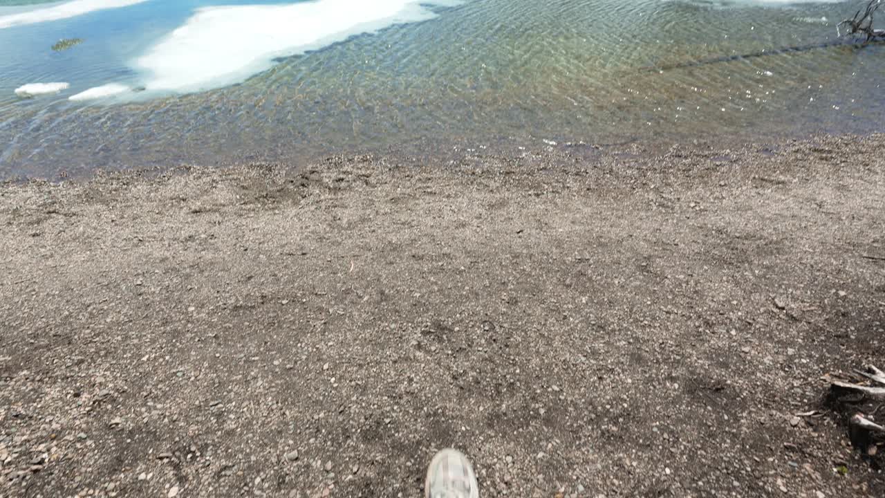 First person view of a hiker reaching the shore of the melting Peyto Lake in the Canadian Rockies in Banff National Park
