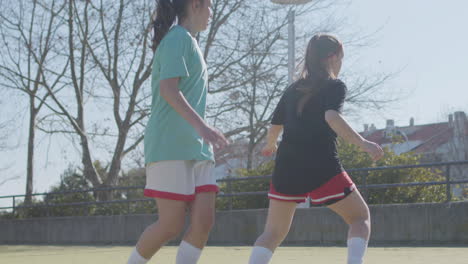 young teenage girls playing football on sunny day