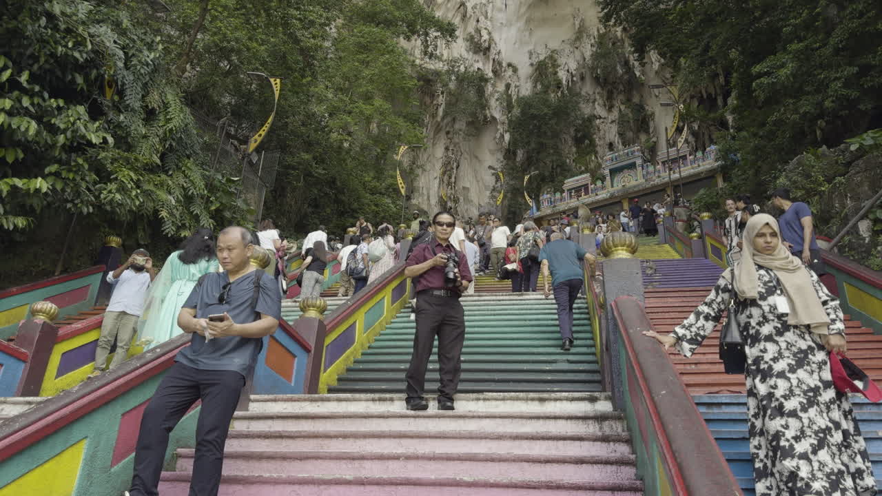 Crowds walking up the colorful steps leading to Batu Caves, a famous tourist attraction