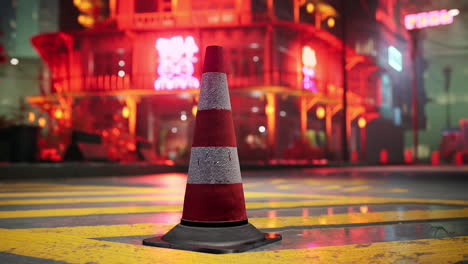 red and white traffic cone on a city street at night