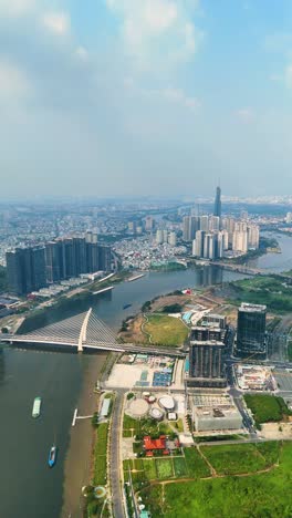 vertical aerial: landmark 81 supertall skyscraper, saigon river, and cityscape during the day in ho chi minh city, vietnam