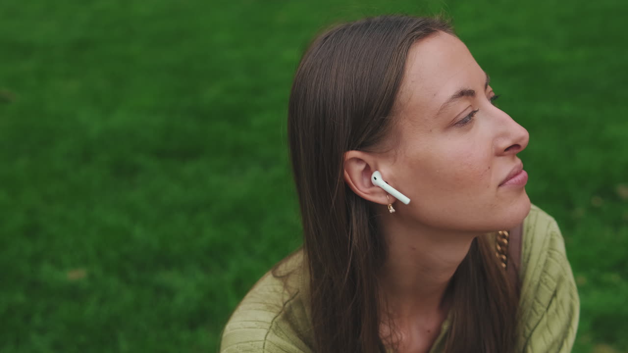 Giovane donna rilassata che ascolta musica con auricolari wireless all'aperto