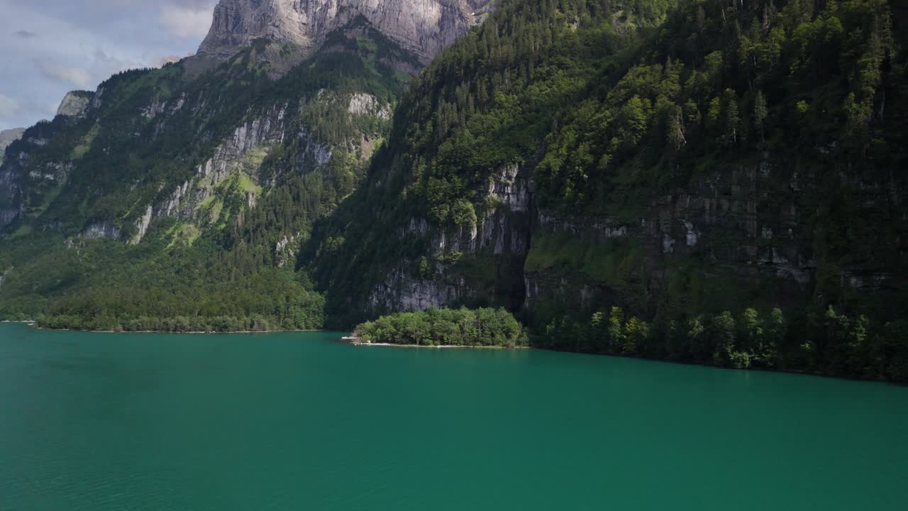Closeup of Klontalersee natural lake shore surrounded with mountains, Glacial lake emerald-green water surface, Aerial view