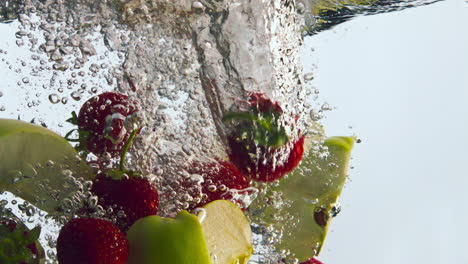 frutas sabrosas salpicando agua en súper cámara lenta de cerca. ingredientes de vitaminas.