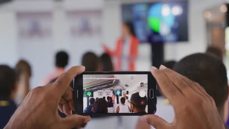 person in audience at a business conference filming with smartphone