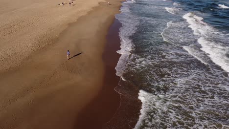 Isolated-young-woman-walking-on-beach-on-sunny-day,-Playa-Brava-in-Uruguay