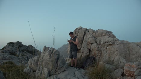 Male-Drone-pilot-with-controller-flying-drone-between-mountains-during-foggy-day