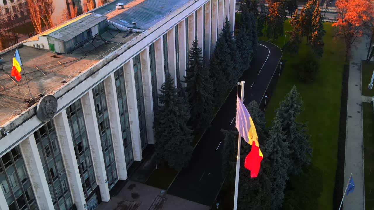 Aerial drone view of Government House at sunset. Building with flag and road in front of it, bare trees in Chisinau, Moldova