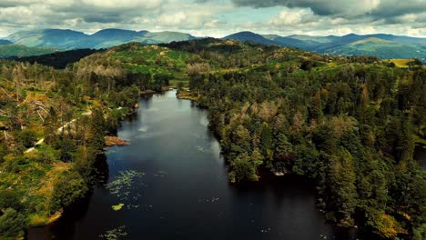 Ariel-footage-of-clouds-rolling-over-mountains-and-hills-with-trees-in-Tarn-Hows-in-the-Lake-District,-Cumbria,-UK