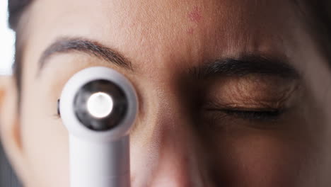 woman using otoscope for an examination, blinking, close up