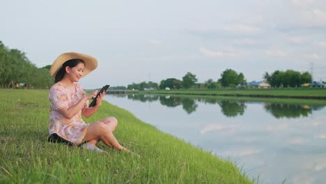 adult woman sitting on the lawn using portable technology