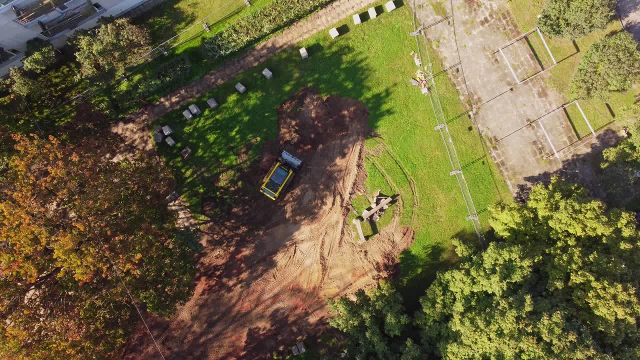 Bagger auf einer Baustelle auf einer Grasfläche in der Nähe eines Wohnviertels.