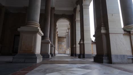 walking between columns in mill colonnade, landmark of karlovy vary, czech republic, low angle view