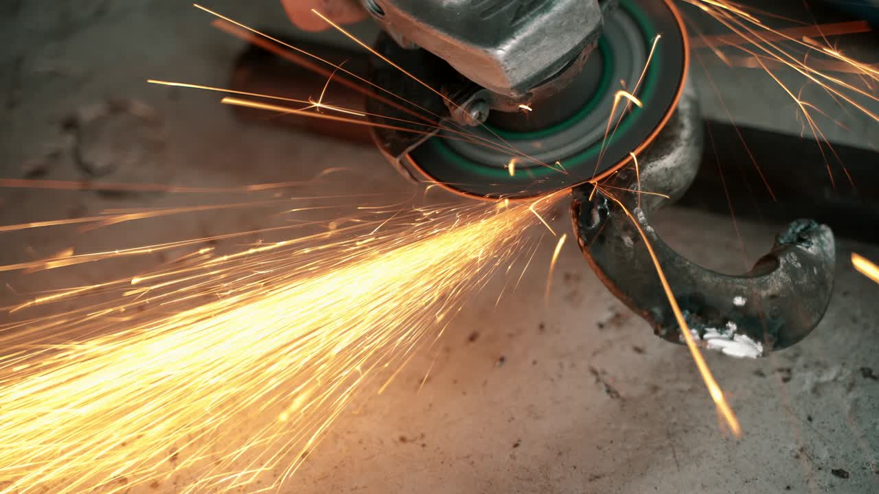 Worker using angle grinder in factory and throwing sparks