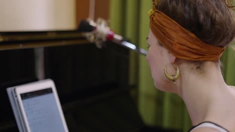 woman singing and playing music with piano and tablet