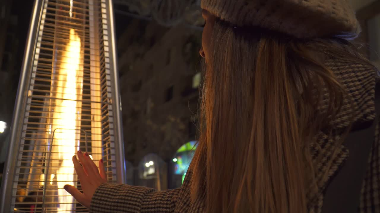 mujer junto a una estufa al aire libre que emite una llama de fuego y luz