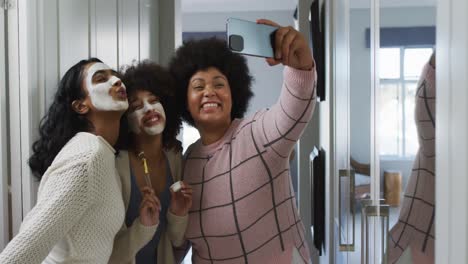 Happy-diverse-female-friends-taking-selfies-with-smartphone-and-smiling-in-bathroom