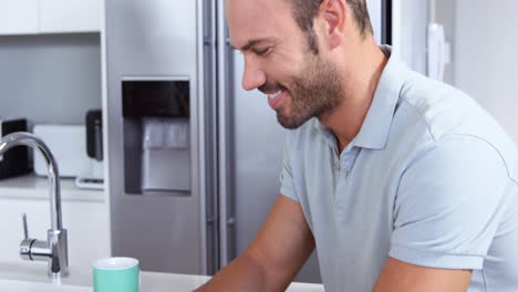 hombre guapo usando una computadora portátil mientras bebe café