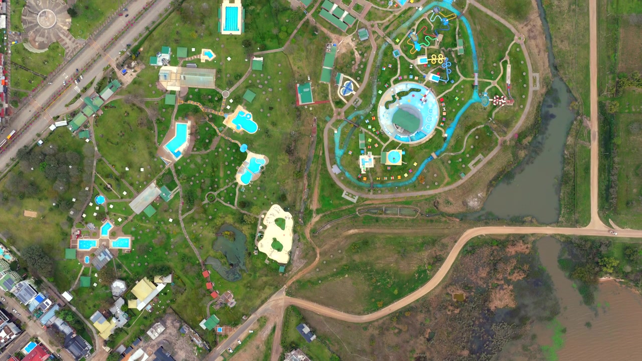A top down aerial view reveals winding turquoise pools and gardens at a popular hot springs complex in Argentina.