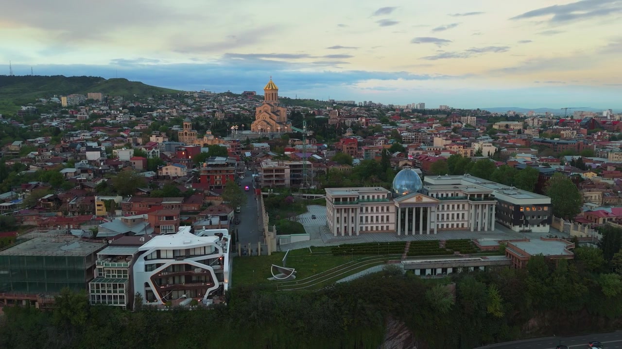 Drone bay quanh Cung điện Tổng thống Tbilisi cùng Nhà thờ Chính thống giáo Ba Ngôi Thánh, hé lộ toàn cảnh thành phố thủ đô Georgia lúc hoàng hôn.