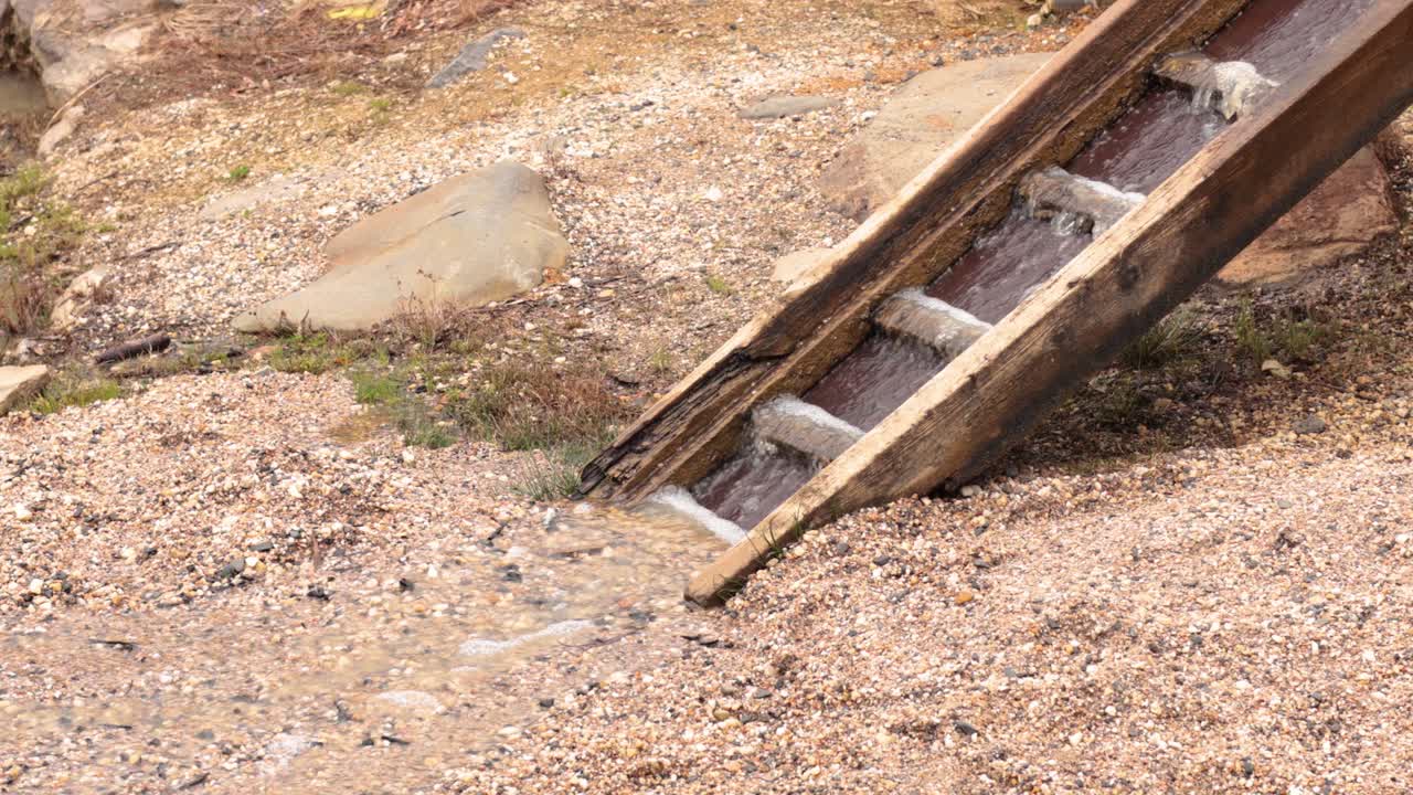 Water flows down a wooden mining chute
