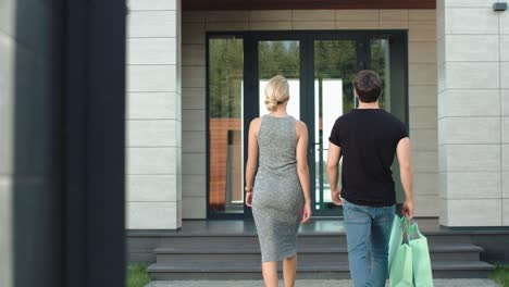 cute couple entering luxury house with shopping bags.