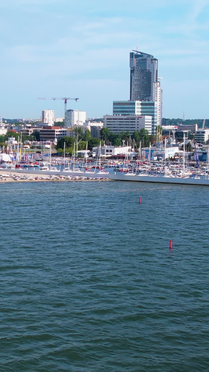 Un'ampia ripresa panoramica della marina di Gdynia che mostra il grattacielo Sea Towers e numerose barche a vela ormeggiate al molo in una giornata limpida