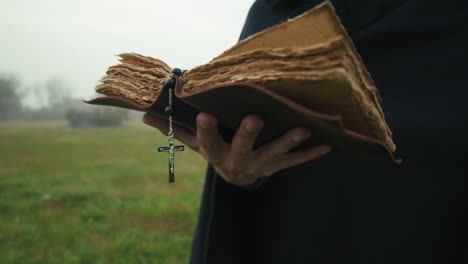 christian bible book read in a dull outdoor park in winter by a priest